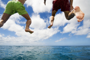 Young men jumping into the sea, low angle view